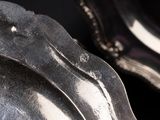 a silver plate with a silver handle on a black background