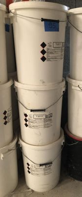 several white buckets are stacked on top of each other in a garage