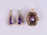 three amethorate and gold pendants on a white surface