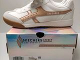 des baskets Skechers blanches et dorées posées sur une boîte
