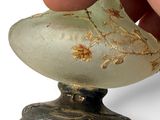 a hand that is holding a piece of glass with a flower on it
