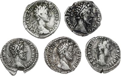 quatre pièces de monnaie romaines antiques, dont l'une représente la tête d'une femme et l'autre celle d'un homme