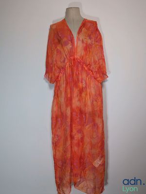 an orange dress on a mannequin stand against a white wall