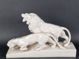 two figurines of lions on a marble base with a black background