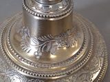 a silver plate with a silver candle on top of it