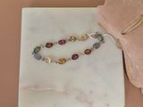 bracelet orné de pierres multicolores sur un fond en marbre, présenté dans une pochette en velours rose