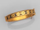 gros plan d'un bracelet en or sur une surface blanche