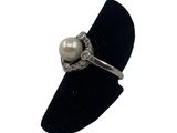 a close up of a ring with a pearl on a black ring stand