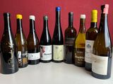 Des bouteilles de vin sont alignées sur une table devant un mur rouge.