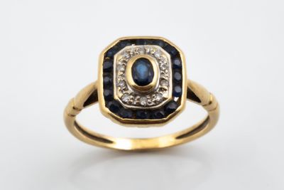 a close up of a gold ring with a sapphire and diamond center