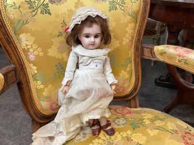 une poupée assise sur une chaise dans une pièce
