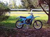 a blue dirt bike parked in front of a white fence