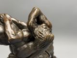 bronze sculpture of a man laying on his back with his hands on his head