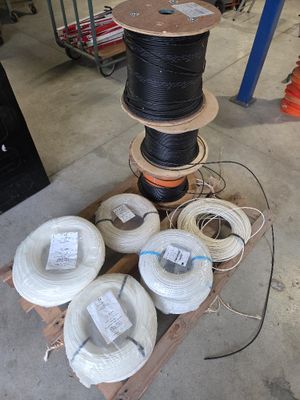 plusieurs rouleaux de fils noirs et blancs sur une palette dans un entrepôt