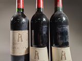 three bottles of red wine are lined up in a row