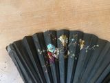 a black fan with flowers on it sitting on a table
