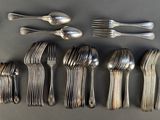 un grand nombre de cuillères et de fourchettes disposées sur une table