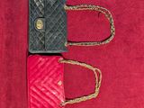 two small handbags are sitting on a red surface