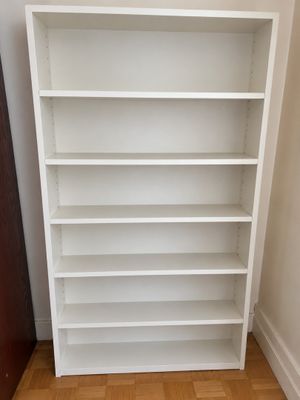 a white bookshelf in a corner of a room with a wooden floor