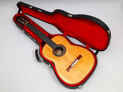 une guitare dans un étui, posée sur une surface blanche