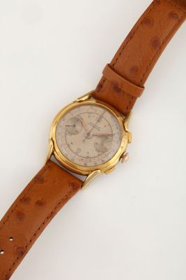 a close up of a watch on a white surface with a brown strap