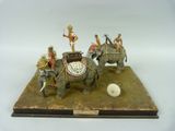 une figurine représentant un groupe de personnes chevauchant des éléphants