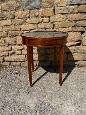 a small wooden table with a glass top on a gravel ground