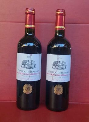 two bottles of red wine sitting on a red table