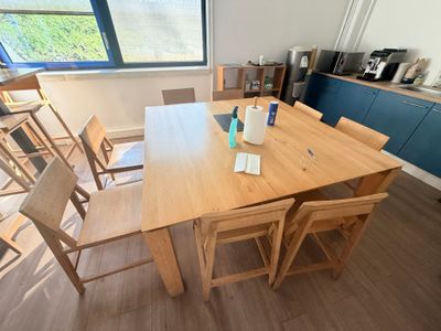 une table et des chaises en bois dans une pièce dotée d'une grande fenêtre