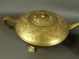a gold teapot sitting on a stand on a table
