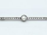 un gros plan d'une bague sertie d'un diamant et d'une perle sur fond blanc