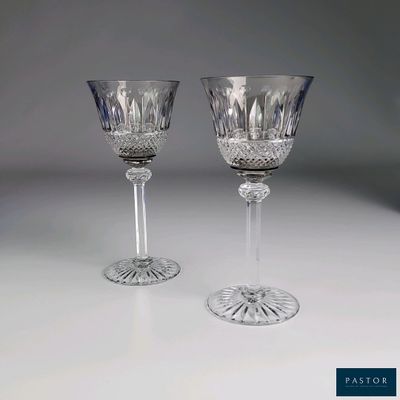 une paire de verres à pied en cristal posés sur une table blanche, sur fond gris