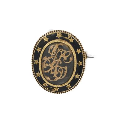 un gros plan d'une bague dorée et noire ornée d'un monogramme