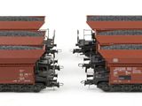 two red train cars sitting side by side on a white surface
