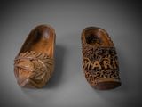 pair of carved wooden shoes on a gray surface