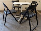 a white table with four black chairs around it