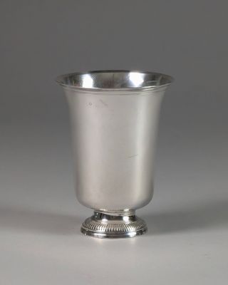 une coupe en argent ancienne posée sur une table blanche