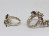 two rings with different colored stones on them sitting next to each other