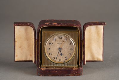 une petite horloge dans un boîtier posé sur une table