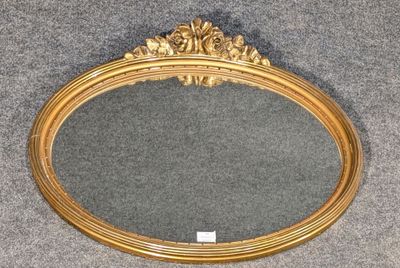 un miroir ovale doré posé sur un sol recouvert de moquette grise