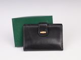 un portefeuille en cuir noir avec un fermoir doré et une boîte verte