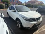 the white nissan qx is parked on the side of the road