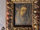 an old picture of a woman in a gold frame on a table