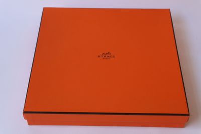 une boîte orange ornée d'un logo, posée sur une surface blanche
