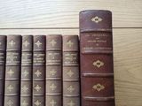 several old books are lined up on a shelf on a wooden table