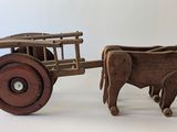 un jouet en bois représentant une vache tirant une charrette sur laquelle se trouve une autre vache
