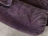 a close up of a purple couch with a pillow on it