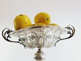 two lemons sitting on top of a silver bowl