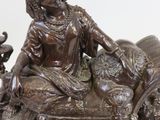 a statue of a woman sitting on a bed with a dog