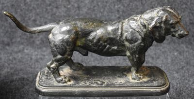 statue of a dog standing on a silver plate on a black background